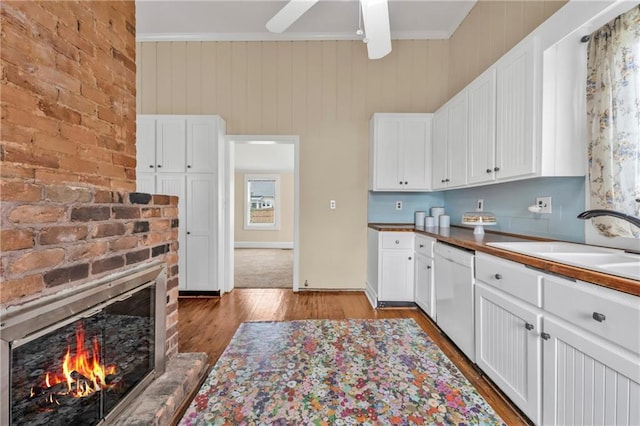 kitchen featuring white cabinets, a fireplace, white dishwasher, and a sink