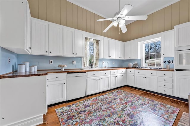 kitchen featuring dishwasher, light wood-type flooring, plenty of natural light, and white cabinetry