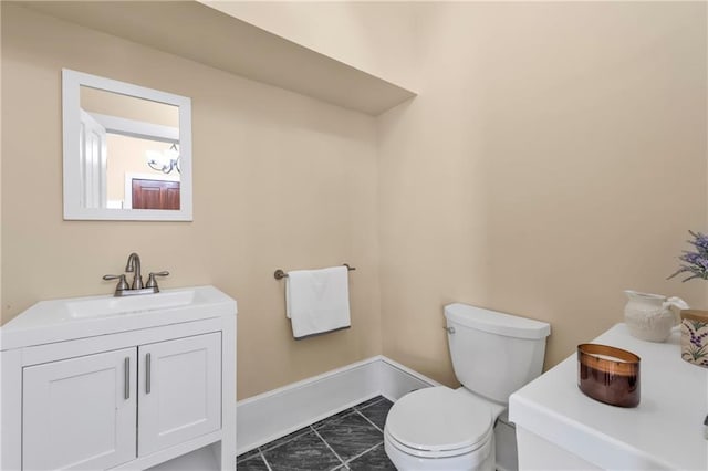 bathroom featuring vanity, toilet, and baseboards