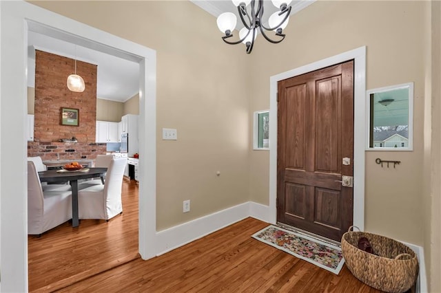 entryway featuring baseboards, ornamental molding, a chandelier, and wood finished floors