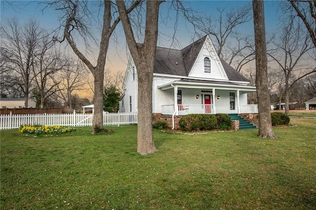 view of front facade with covered porch, a front lawn, and fence