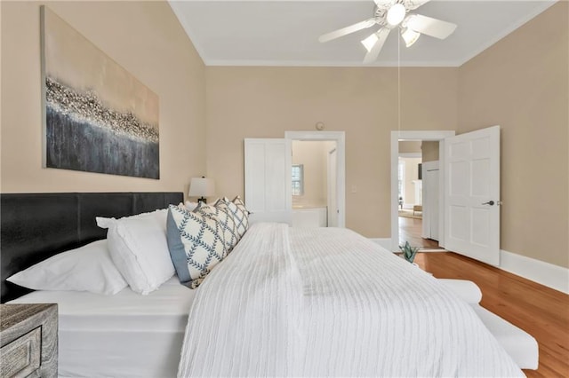 bedroom with baseboards, ensuite bath, ceiling fan, wood finished floors, and crown molding