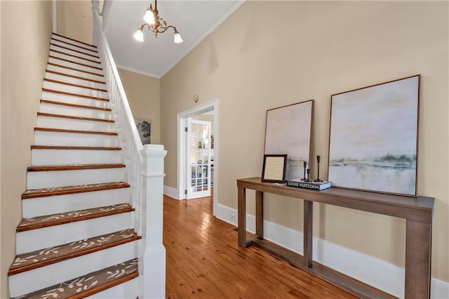 stairway featuring baseboards, ornamental molding, wood finished floors, vaulted ceiling, and a chandelier