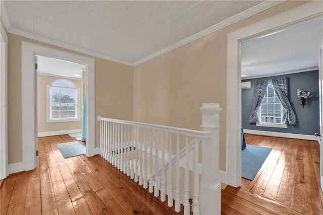 hallway featuring ornamental molding, hardwood / wood-style flooring, an upstairs landing, and baseboards