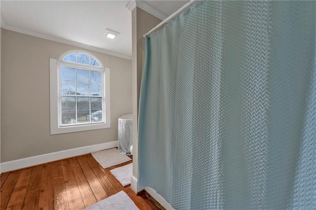 bathroom featuring hardwood / wood-style floors, baseboards, crown molding, and a shower with shower curtain