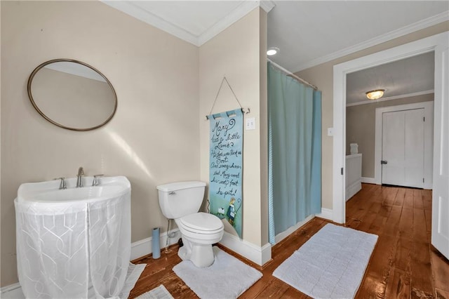 bathroom featuring baseboards, crown molding, toilet, and wood finished floors