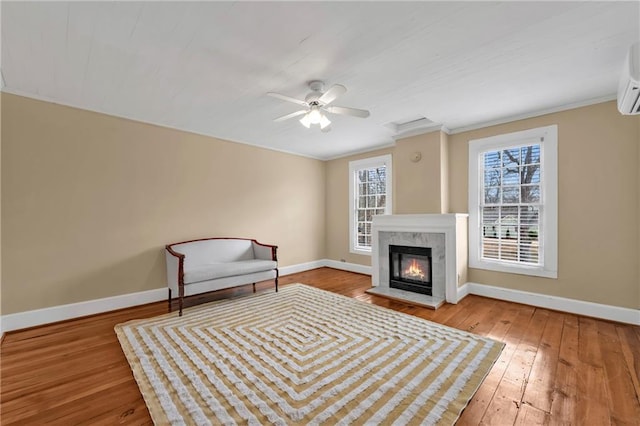 unfurnished room with hardwood / wood-style floors, a ceiling fan, a high end fireplace, and baseboards