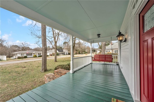 wooden deck with a residential view, a porch, and a yard