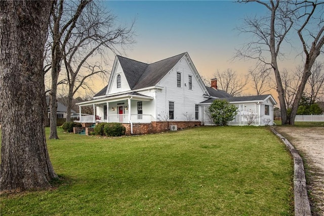 view of side of property with driveway, covered porch, a yard, and a chimney