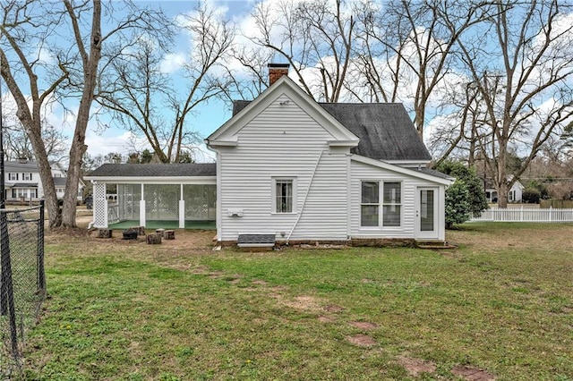 rear view of property featuring a yard, a chimney, fence, and a sunroom