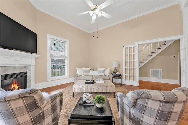 living room featuring a premium fireplace, wood finished floors, visible vents, and crown molding