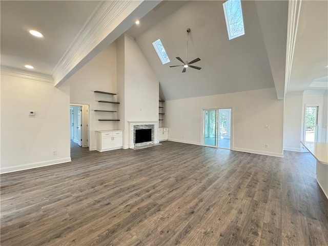 unfurnished living room featuring ornamental molding, dark wood-type flooring, a high end fireplace, and a skylight