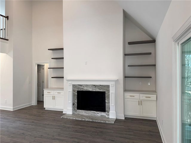 unfurnished living room with dark hardwood / wood-style flooring, a high end fireplace, and high vaulted ceiling