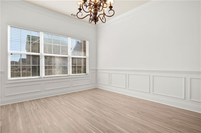 spare room with ornamental molding, hardwood / wood-style floors, and a notable chandelier