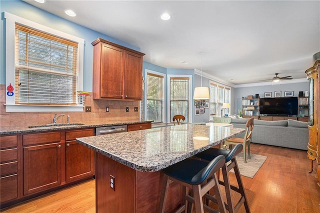 kitchen featuring light hardwood / wood-style flooring, decorative light fixtures, sink, backsplash, and a center island