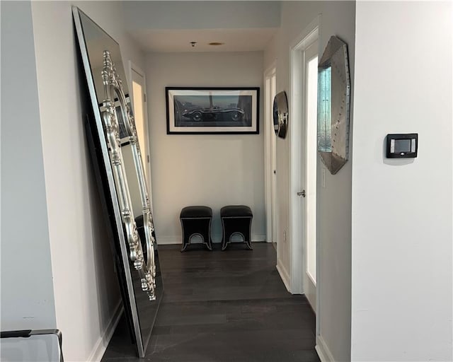 corridor featuring baseboards and dark wood-style flooring