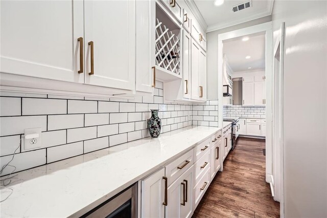 kitchen with light stone counters, crown molding, white cabinets, and dark wood-type flooring