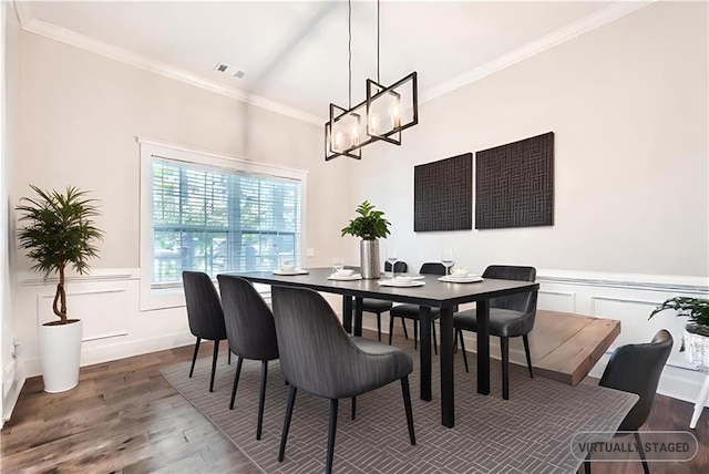 dining space with hardwood / wood-style floors, crown molding, and a notable chandelier