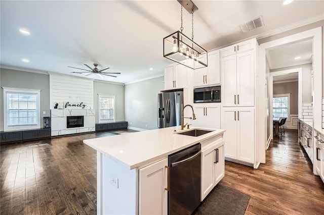 kitchen featuring appliances with stainless steel finishes, sink, white cabinets, hanging light fixtures, and an island with sink