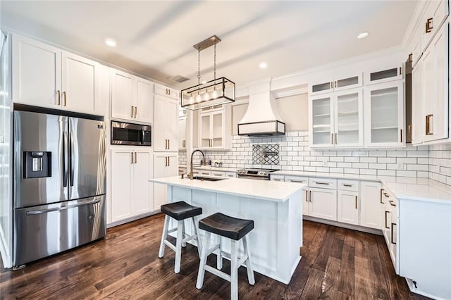 kitchen featuring sink, stainless steel appliances, a kitchen island with sink, white cabinets, and custom exhaust hood