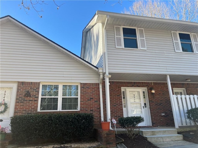 view of property featuring covered porch and brick siding