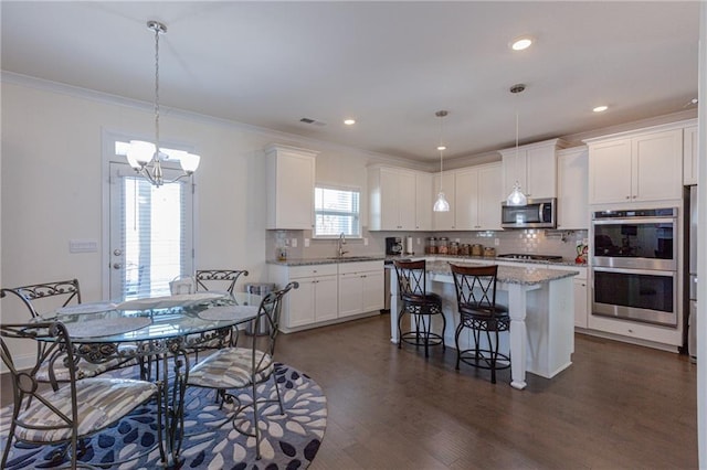 kitchen featuring tasteful backsplash, white cabinetry, stainless steel appliances, and a kitchen island