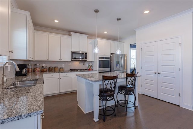 kitchen featuring white cabinets, appliances with stainless steel finishes, a center island, tasteful backsplash, and sink