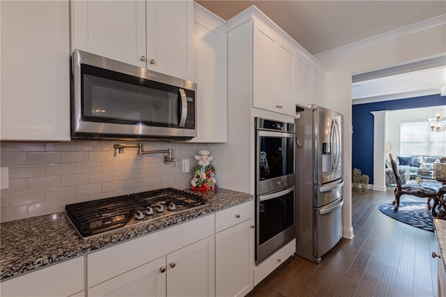 kitchen featuring backsplash, white cabinetry, appliances with stainless steel finishes, and dark stone counters