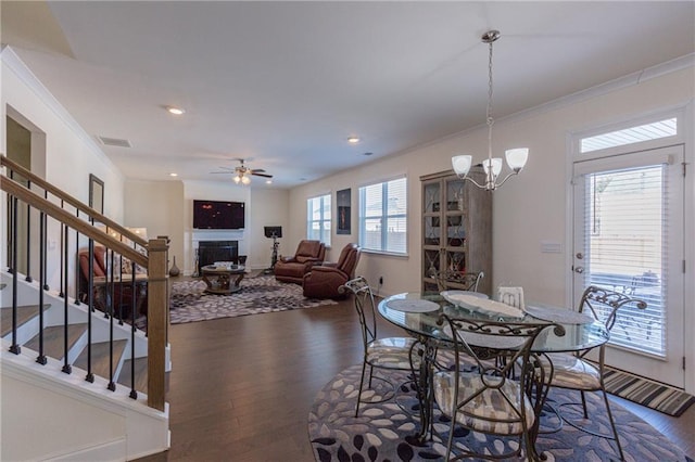 dining space featuring ceiling fan with notable chandelier, dark hardwood / wood-style flooring, and ornamental molding