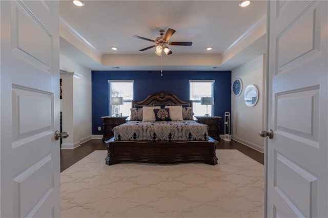 bedroom featuring ceiling fan, dark wood-type flooring, and a raised ceiling