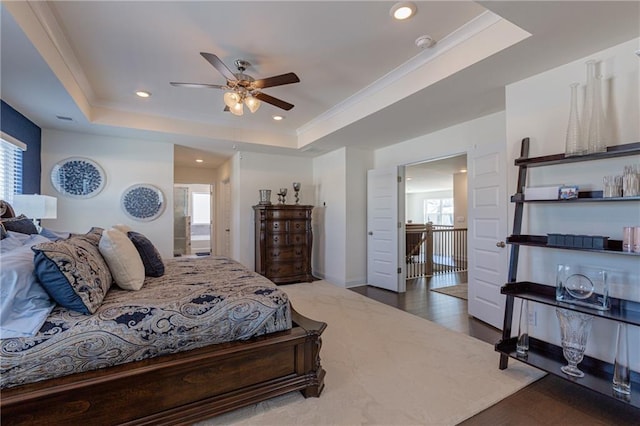 bedroom with ceiling fan, hardwood / wood-style flooring, ornamental molding, and a raised ceiling