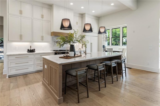 320 Shady Grove Ln, Alpharetta, GA 30009 - kitchen with light wood-style floors, a center island with sink, recessed lighting, white cabinetry, and a breakfast bar