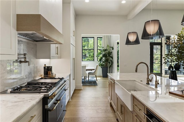 320 Shady Grove Ln, Alpharetta, GA 30009 - kitchen with range with two ovens, a sink, light wood-style floors, wall chimney range hood, and light stone counters