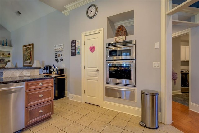 kitchen with a warming drawer, stainless steel appliances, light tile patterned flooring, baseboards, and crown molding