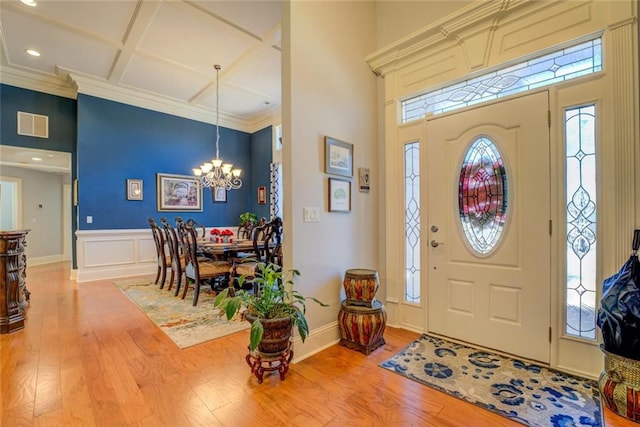 foyer entrance with coffered ceiling, light wood-type flooring, a chandelier, plenty of natural light, and recessed lighting