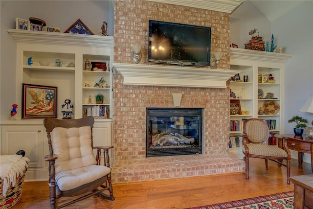 living room with wood finished floors, a fireplace, and built in features