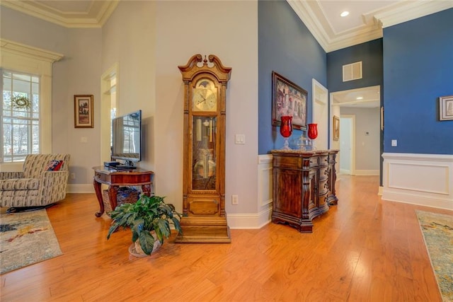 corridor with a towering ceiling, wood finished floors, ornamental molding, recessed lighting, and baseboards