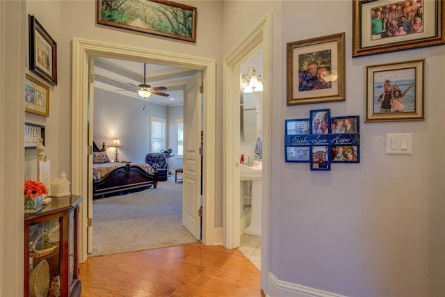 hallway featuring light wood finished floors and baseboards