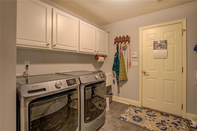 washroom with cabinet space, washer and clothes dryer, dark tile patterned floors, and baseboards