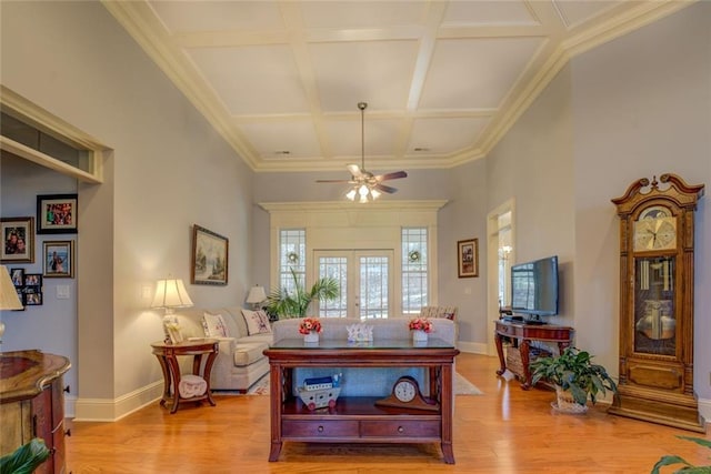 living room with coffered ceiling, light wood-style floors, ceiling fan, baseboards, and beamed ceiling
