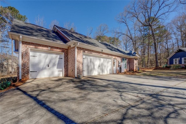 view of side of home featuring driveway, a garage, and brick siding
