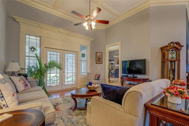 living area featuring french doors, coffered ceiling, ornamental molding, ceiling fan, and wood finished floors