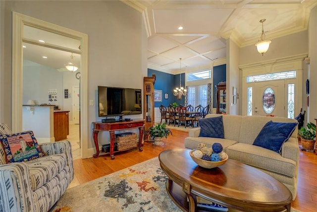 living area featuring coffered ceiling, a chandelier, wood finished floors, ornamental molding, and recessed lighting
