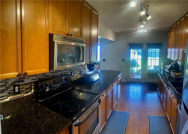750 Dalrymple Rd Unit G3, Atlanta, GA 30328 - kitchen featuring stainless steel microwave, range with electric cooktop, backsplash, dark stone countertops, and wood finished floors