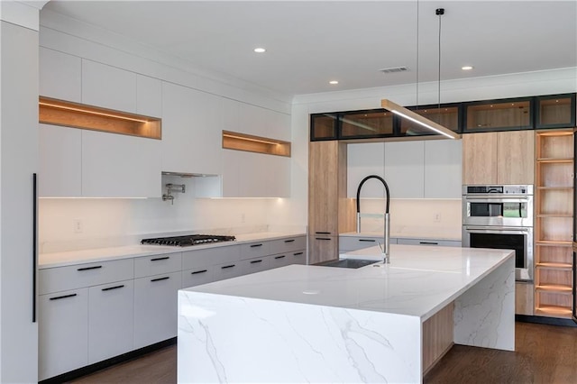 kitchen with a kitchen island with sink, dark wood-type flooring, hanging light fixtures, light stone countertops, and appliances with stainless steel finishes