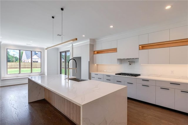 kitchen with sink, white cabinetry, and a kitchen island with sink