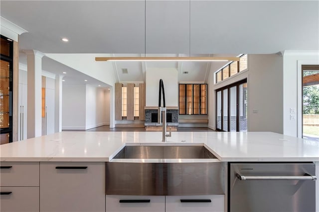 kitchen featuring light stone counters, white cabinetry, and sink