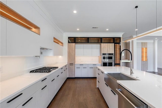 kitchen featuring appliances with stainless steel finishes, dark hardwood / wood-style flooring, sink, white cabinets, and hanging light fixtures