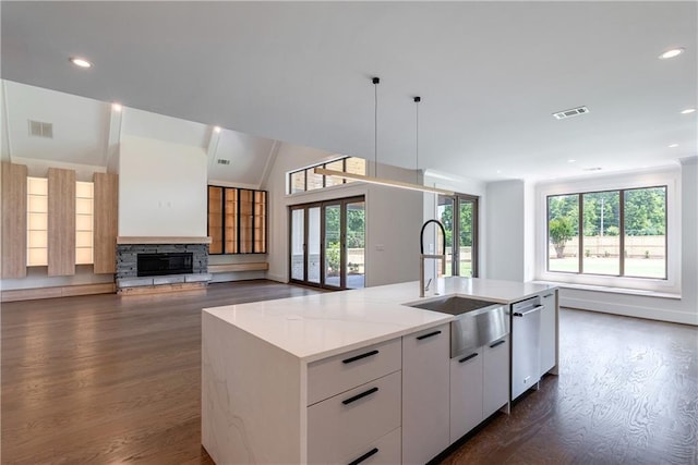 kitchen featuring light stone counters, stainless steel dishwasher, sink, a center island with sink, and white cabinets