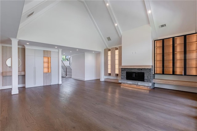 unfurnished living room with beamed ceiling, high vaulted ceiling, a stone fireplace, and ornate columns